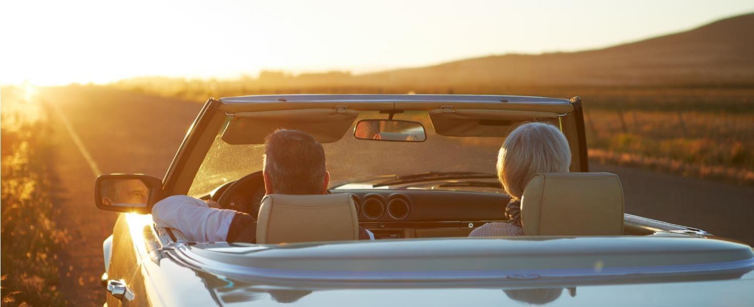 senior couple in a convertible enjoying the sunset